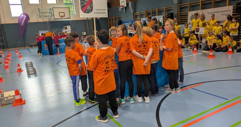 Turnhalle in Langkampfen, die Kinder der 3a Klasse stehen zusammen in orangen T-Shirts mit ihrem Schulschild