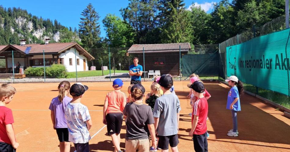 Tennisplatz Lechaschau bei herrlichem Sonnenschein- die Kinder stehen um den Tennislehrer